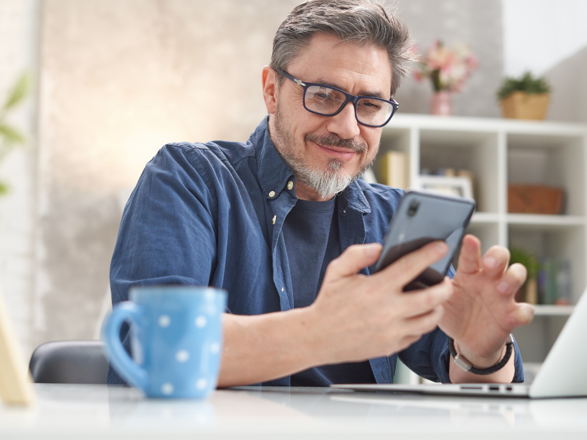 Άνδρας που χρησιμοποιεί κινητό και αναμένει να ενημερωθεί για πρόγραμμα ενέργειας με τη βοήθεια εκπροσώπου.