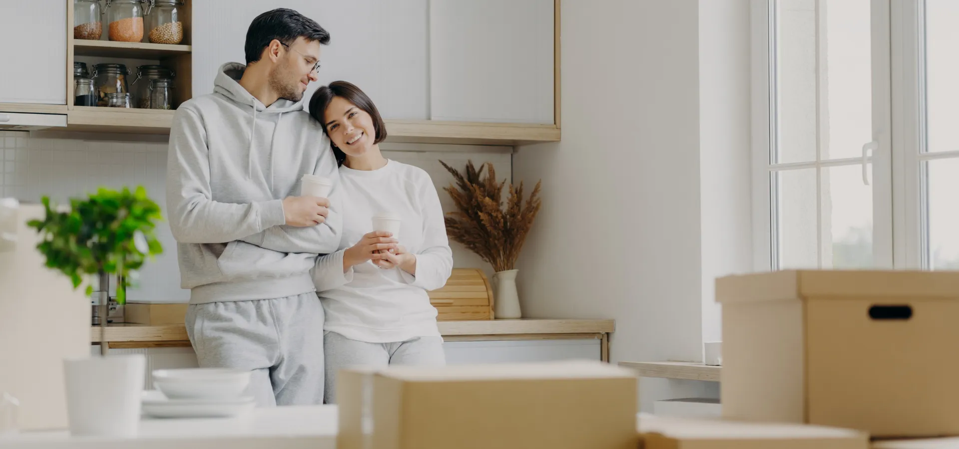 ζευγάρι που χαλαρώνει στην νέα του κουζίνα με κούτες απο μετακόμιση