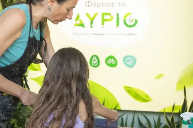 μία δασκάλα μεταξοτυπίας που δείχνει σε ένα κοριτσάκι πως να φτιάξει tote bag στο κέντρο πολιτισμού ίδρυμα Σταύρος Νιάρχος κατά την διάρκεια του Green Weekend